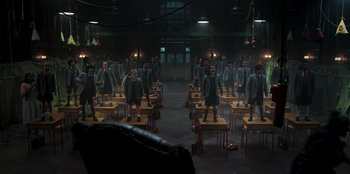 Movie still from “Roald Dahl's Matilda the Musical” (2022), directed by Matthew Warchus – A group of people standing in a room with tables; Wide shot, High angle