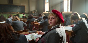 Movie still from “Roald Dahl's Matilda the Musical” (2022), directed by Matthew Warchus – A girl in a red beret sits in a classroom; Close Up shot, Low angle