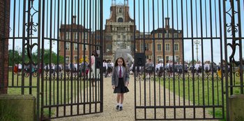 Movie still from “Roald Dahl's Matilda the Musical” (2022), directed by Matthew Warchus – A little girl standing in front of an open gate; Extreme Wide shot, High angle