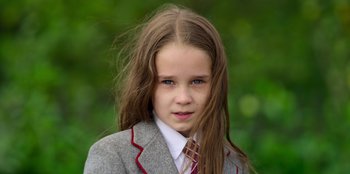 Movie still from “Roald Dahl's Matilda the Musical” (2022), directed by Matthew Warchus – A young girl in a suit and tie with long hair; Close Up shot, High angle