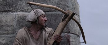 Movie still from “Robin Hood” (2010), directed by Ridley Scott – An old man holding a bow and arrow in his hands; Close Up shot, Over the shoulder angle