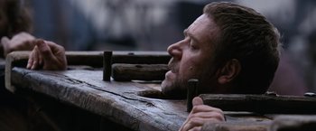 Movie still from “Robin Hood” (2010), directed by Ridley Scott – A person leaning over a wooden bench; Close Up shot, Low angle