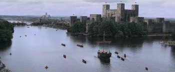 Movie still from “Robin Hood” (2010), directed by Ridley Scott – A group of boats in a body of water near a castle; Extreme Wide shot, High angle