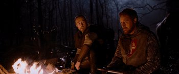 Movie still from “Robin Hood” (2010), directed by Ridley Scott – Two men sitting in front of a fire in the woods; Medium shot, Low angle