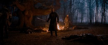 Movie still from “Robin Hood” (2010), directed by Ridley Scott – A man and a woman standing next to a fire in the woods; Wide shot, Low angle