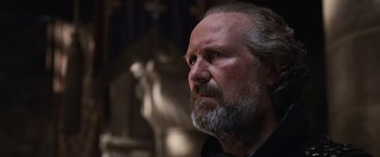 Movie still from “Robin Hood” (2010), directed by Ridley Scott – An older man with a beard looking to his left; Close Up shot, Low angle
