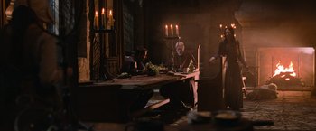 Movie still from “Robin Hood” (2010), directed by Ridley Scott – Two men sitting at a dinner table with candles in the background; Wide shot, High angle