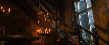 Movie still from “Robin Hood” (2010), directed by Ridley Scott – A chandelier hanging from the railing of the stairs; Wide shot, High angle
