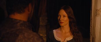 Movie still from “Robin Hood” (2010), directed by Ridley Scott – A woman is looking at the camera while standing in front of a stone wall; Close Up shot, Over the shoulder angle