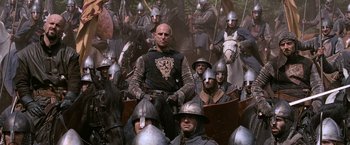 Movie still from “Robin Hood” (2010), directed by Ridley Scott – A man sitting in front of a group of people; Medium shot, Low angle