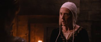 Movie still from “Robin Hood” (2010), directed by Ridley Scott – An older woman wearing a white head covering; Close Up shot, Over the shoulder angle