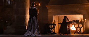 Movie still from “Robin Hood” (2010), directed by Ridley Scott – A woman dressed in medieval garb standing in front of a fireplace; Wide shot, Over the shoulder angle