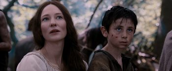 Movie still from “Robin Hood” (2010), directed by Ridley Scott – A woman standing next to a young boy in front of trees; Close Up shot, Low angle