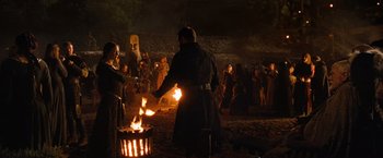 Movie still from “Robin Hood” (2010), directed by Ridley Scott – A group of people standing next to a fire pit; Wide shot, Over the shoulder angle