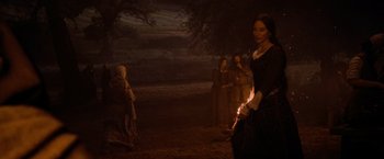 Movie still from “Robin Hood” (2010), directed by Ridley Scott – A woman holding a lit candle in front of a group of people; Wide shot, Over the shoulder angle