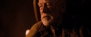Movie still from “Robin Hood” (2010), directed by Ridley Scott – An old man with a beard wearing a fur coat; Close Up shot, Over the shoulder angle