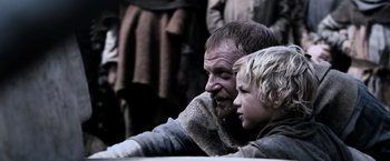 Movie still from “Robin Hood” (2010), directed by Ridley Scott – A man and a boy sitting next to each other; Medium shot, Low angle