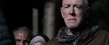 Movie still from “Robin Hood” (2010), directed by Ridley Scott – An older man wearing a chain around his neck; Close Up shot, Low angle