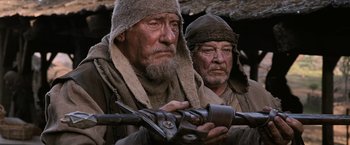 Movie still from “Robin Hood” (2010), directed by Ridley Scott – A man holding a gun while standing next to another man; Close Up shot, Low angle