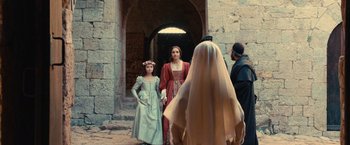 Movie still from “Benedetta” (2021), directed by Paul Verhoeven – Two women in medieval garb and a man in a hooded cloak; Wide shot, Over the shoulder angle