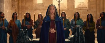 Movie still from “Benedetta” (2021), directed by Paul Verhoeven – A woman standing in front of a group of people; Medium shot, Over the shoulder angle