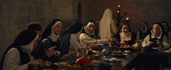 Movie still from “Benedetta” (2021), directed by Paul Verhoeven – A group of people sitting at a table with food on it; Medium shot, High angle