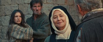 Movie still from “Benedetta” (2021), directed by Paul Verhoeven – An older man and a younger woman in front of a stone wall; Medium shot, Over the shoulder angle