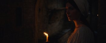 Movie still from “Benedetta” (2021), directed by Paul Verhoeven – A woman holding a lit candle in a dark room; Close Up shot, Over the shoulder angle