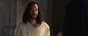 Movie still from “Benedetta” (2021), directed by Paul Verhoeven – A man with long hair and a white shirt; Close Up shot, Over the shoulder angle