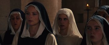 Movie still from “Benedetta” (2021), directed by Paul Verhoeven – Two women dressed in medieval clothing standing next to each other; Close Up shot, Low angle