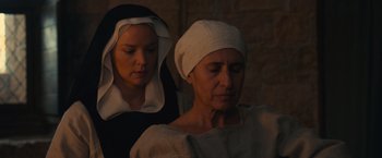 Movie still from “Benedetta” (2021), directed by Paul Verhoeven – Two women in white hats are looking at each other; Close Up shot, High angle