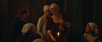 Movie still from “Benedetta” (2021), directed by Paul Verhoeven – Two women are lighting a candle in a dark room; Medium shot, Low angle