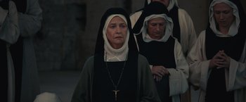 Movie still from “Benedetta” (2021), directed by Paul Verhoeven – A woman wearing a nun's outfit with a cross in front of her face; Close Up shot, Low angle