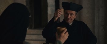Movie still from “Benedetta” (2021), directed by Paul Verhoeven – A man holding a cup in front of his face; Close Up shot, Over the shoulder angle