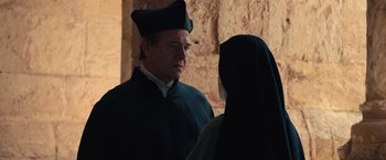 Movie still from “Benedetta” (2021), directed by Paul Verhoeven – A man and a woman wearing black clothes; Medium shot, Over the shoulder angle