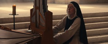Movie still from “Benedetta” (2021), directed by Paul Verhoeven – A woman sitting in front of a pipe organ; Medium shot, Low angle