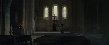 Movie still from “Benedetta” (2021), directed by Paul Verhoeven – A person is standing in front of a cross in a church; Extreme Wide shot, Low angle