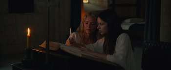 Movie still from “Benedetta” (2021), directed by Paul Verhoeven – Two women sitting in front of an open book; Medium shot, High angle