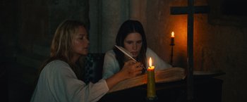 Movie still from “Benedetta” (2021), directed by Paul Verhoeven – Two women sitting in front of a lit candle; Medium shot, High angle