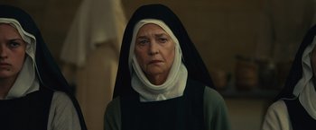 Movie still from “Benedetta” (2021), directed by Paul Verhoeven – An older woman wearing a nun's outfit; Close Up shot, Low angle