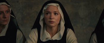 Movie still from “Benedetta” (2021), directed by Paul Verhoeven – A woman wearing a nun's habit and a necklace; Close Up shot, High angle