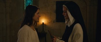 Movie still from “Benedetta” (2021), directed by Paul Verhoeven – A nun showing a girl something on her phone; Medium shot, Over the shoulder angle