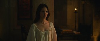 Movie still from “Benedetta” (2021), directed by Paul Verhoeven – A woman in a white dress standing next to a wall; Medium shot, Over the shoulder angle