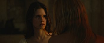 Movie still from “Benedetta” (2021), directed by Paul Verhoeven – A woman looking into a mirror in a dimly - lit room; Close Up shot, Over the shoulder angle