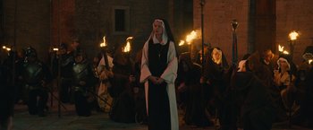 Movie still from “Benedetta” (2021), directed by Paul Verhoeven – A woman dressed as a nun standing in front of a group of people; Wide shot, High angle