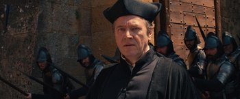 Movie still from “Benedetta” (2021), directed by Paul Verhoeven – A person wearing a hat; Medium shot, Over the shoulder angle