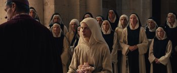 Movie still from “Benedetta” (2021), directed by Paul Verhoeven – A group of people dressed as nuns in front of a wall; Medium shot, Over the shoulder angle