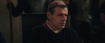 Movie still from “Benedetta” (2021), directed by Paul Verhoeven – A person wearing a hat; Close Up shot, Over the shoulder angle