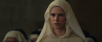 Movie still from “Benedetta” (2021), directed by Paul Verhoeven – A woman wearing a head scarf and a white robe; Close Up shot, Over the shoulder angle