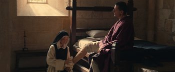 Movie still from “Benedetta” (2021), directed by Paul Verhoeven – An old woman and a man sitting on a bed; Medium shot, High angle